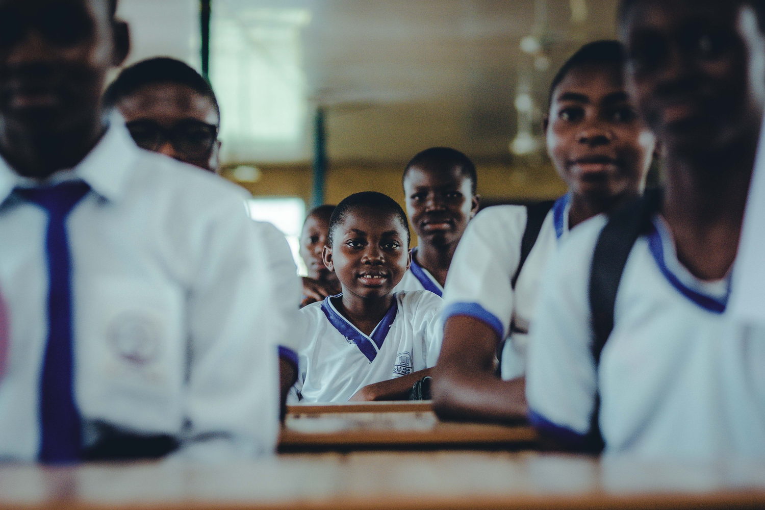 Pupils in school uniform seated together during a lesson in a Nigerian classroom.