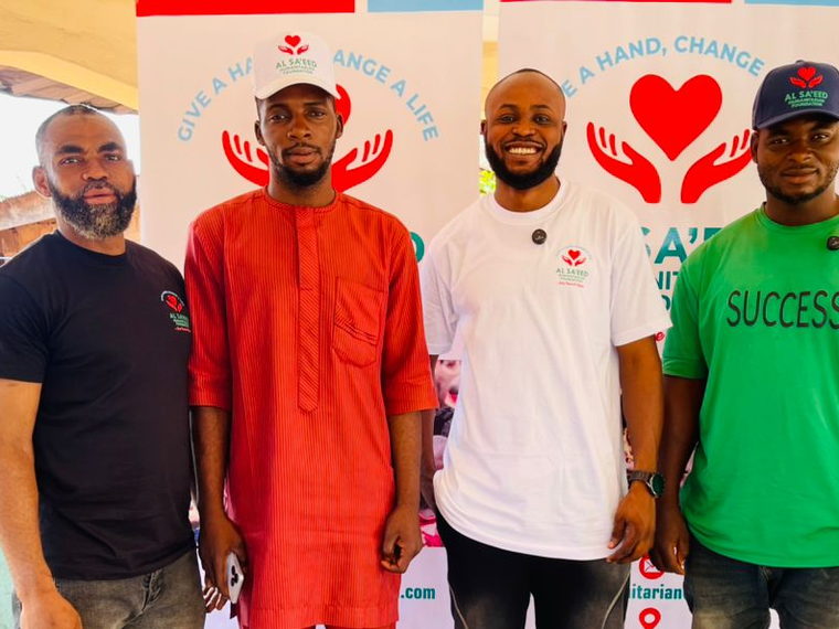 Four members of the Al Sa'eed Humanitarian Foundation team in branded shirts and caps during an outreach.